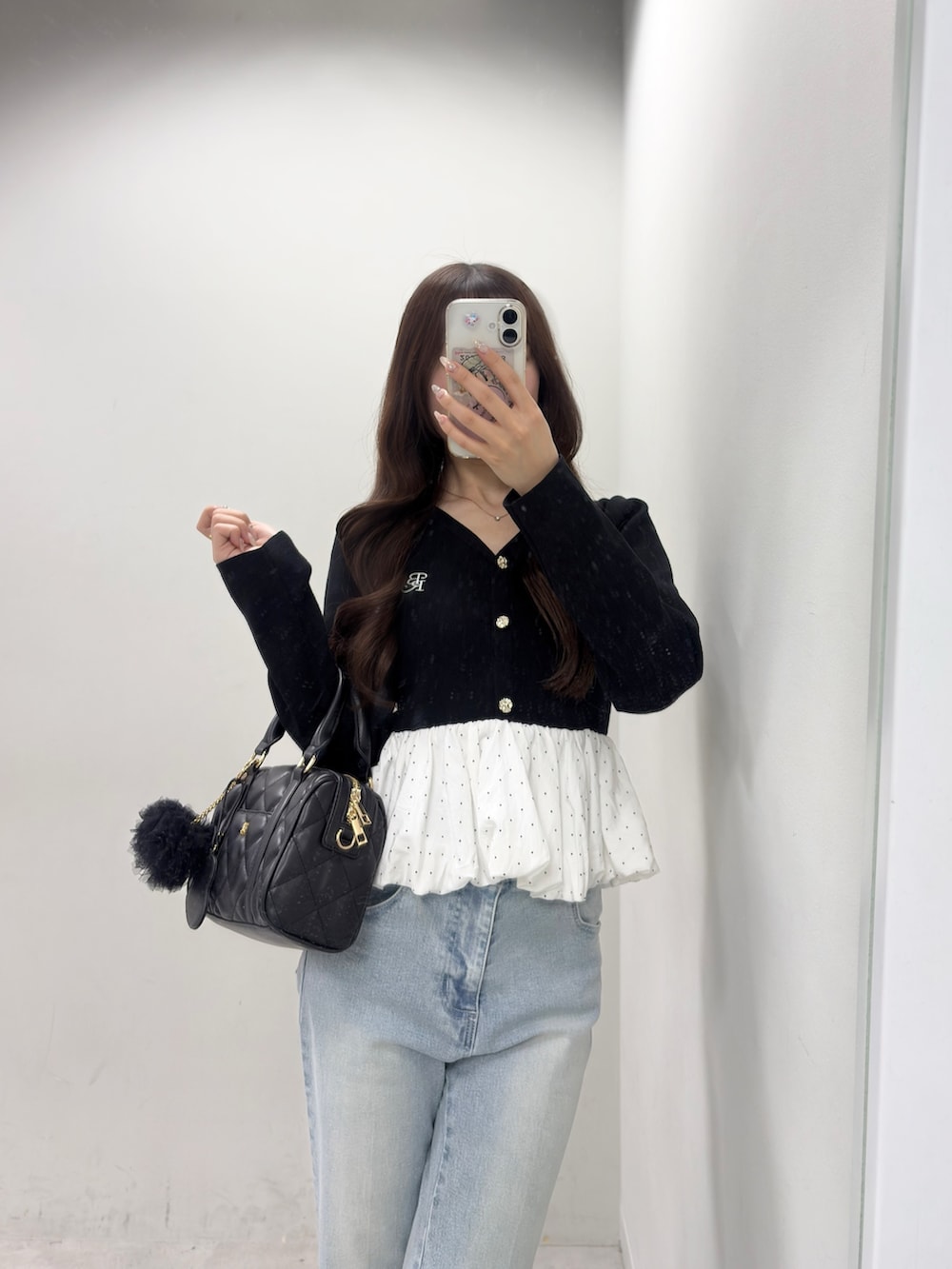 ブラック系のニット/セーター、ブルー系のデニムパンツ、ブラック系のボストンバッグを着用したレディースの春コーディネートの2枚目の写真