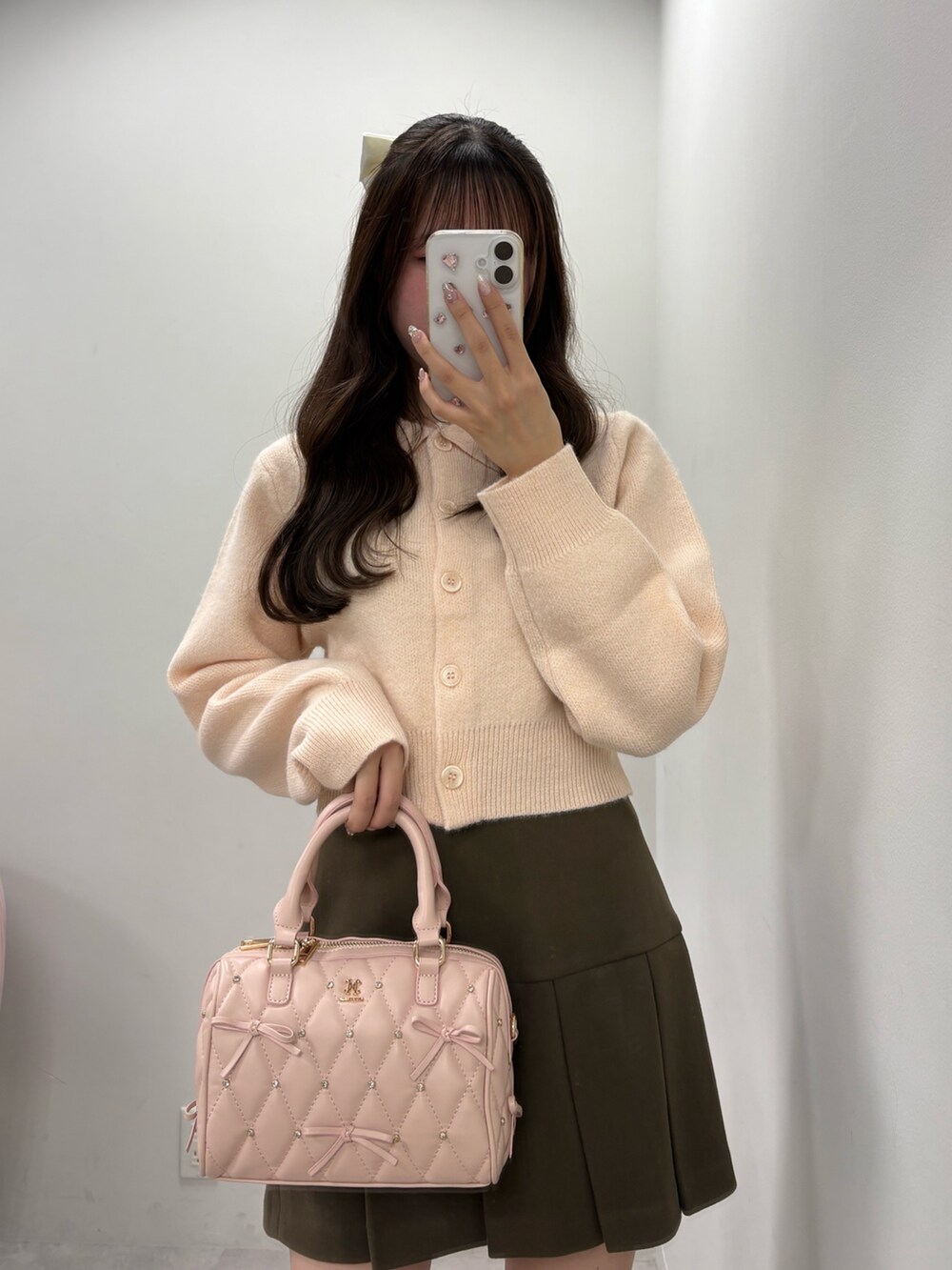 ピンク系のニット/セーター、ブラウン系のスカート、ベージュ系のブーツを着用したレディースの冬コーディネートの2枚目の写真