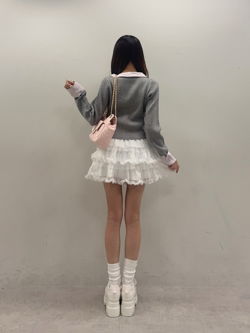 グレー系のニット/セーター、ホワイト系のスニーカー、ホワイト系のスカートを着用したレディースの冬コーディネートの2枚目の写真