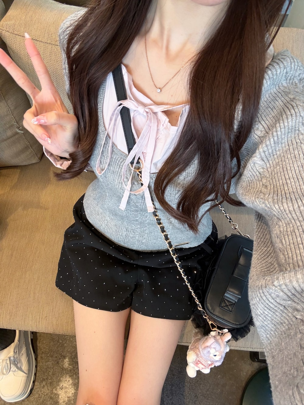 グレー系のニット/セーター、グレー系のスニーカー、ブラック系のショルダーバッグを着用したレディースの冬コーディネートの3枚目の写真