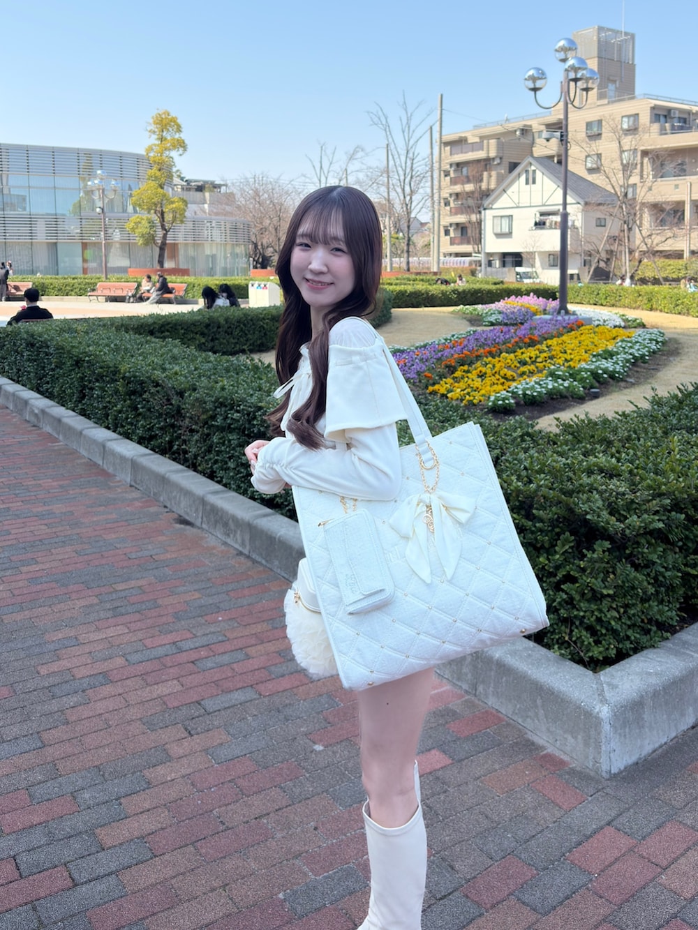 ホワイト系のTシャツ/カットソー、ベージュ系のスカート、ホワイト系のショルダーバッグを着用したレディースの春コーディネートの2枚目の写真