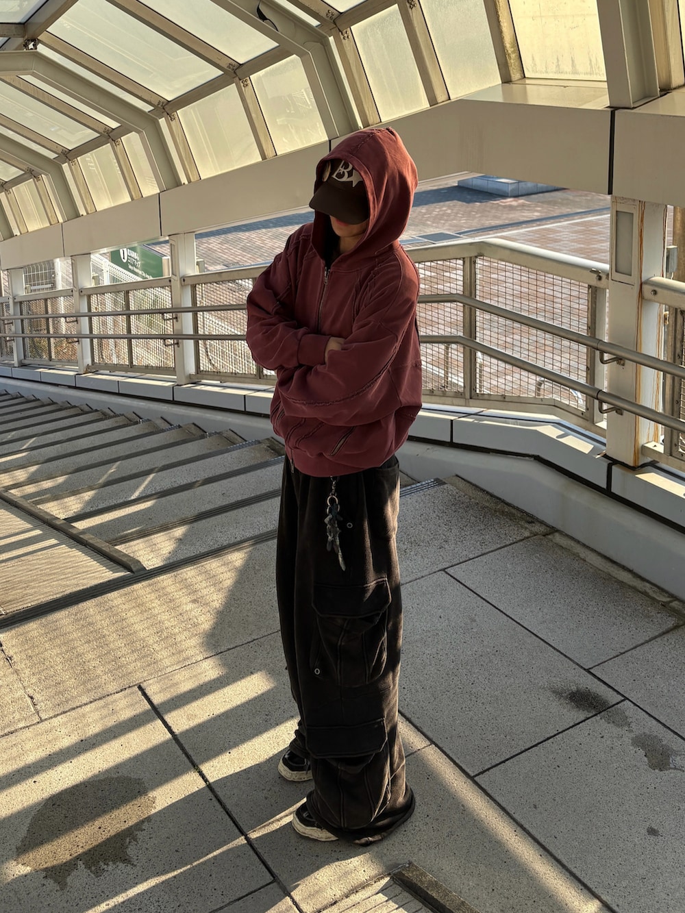 レッド系のパーカー、ブラック系のスウェットパンツを着用したメンズの秋コーディネートの2枚目の写真