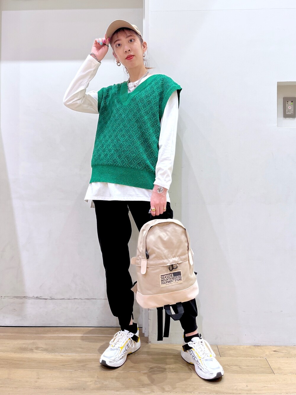 グリーン系のベスト、ホワイト系のTシャツ/カットソー、ベージュ系のバックパック/リュックを着用したレディースの冬コーディネートの2枚目の写真