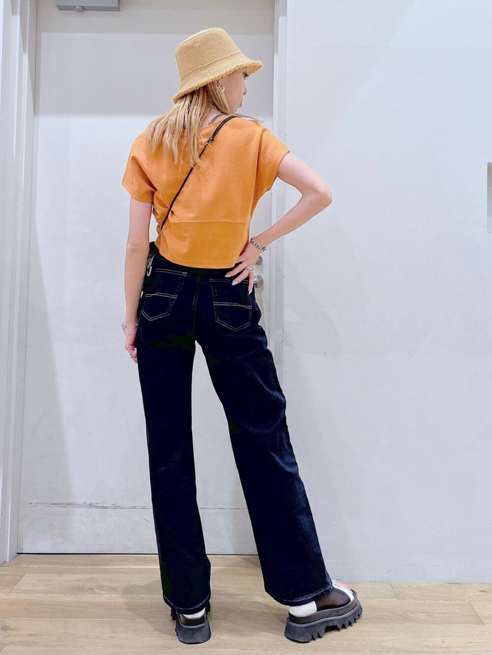 オレンジ系のTシャツ/カットソー、ブラウン系のショルダーバッグ、ブルー系のデニムパンツを着用したレディースの春コーディネートの7枚目の写真