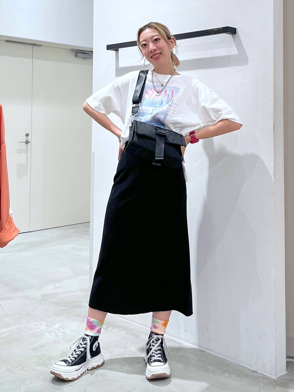 ブラック系のショルダーバッグ、ピンク系のTシャツ/カットソー、ブラック系のスカートを着用したレディースの夏コーディネートの2枚目の写真