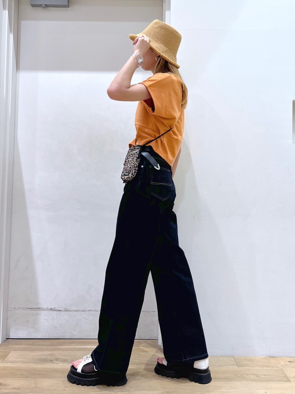 オレンジ系のTシャツ/カットソー、ブラウン系のショルダーバッグ、ブルー系のデニムパンツを着用したレディースの春コーディネートの8枚目の写真