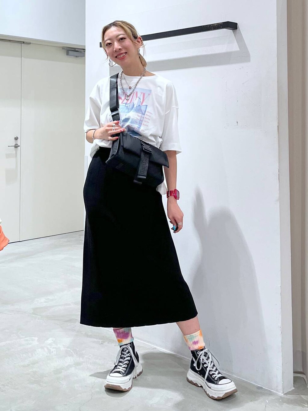 ブラック系のショルダーバッグ、ピンク系のTシャツ/カットソー、ブラック系のスカートを着用したレディースの夏コーディネートの3枚目の写真