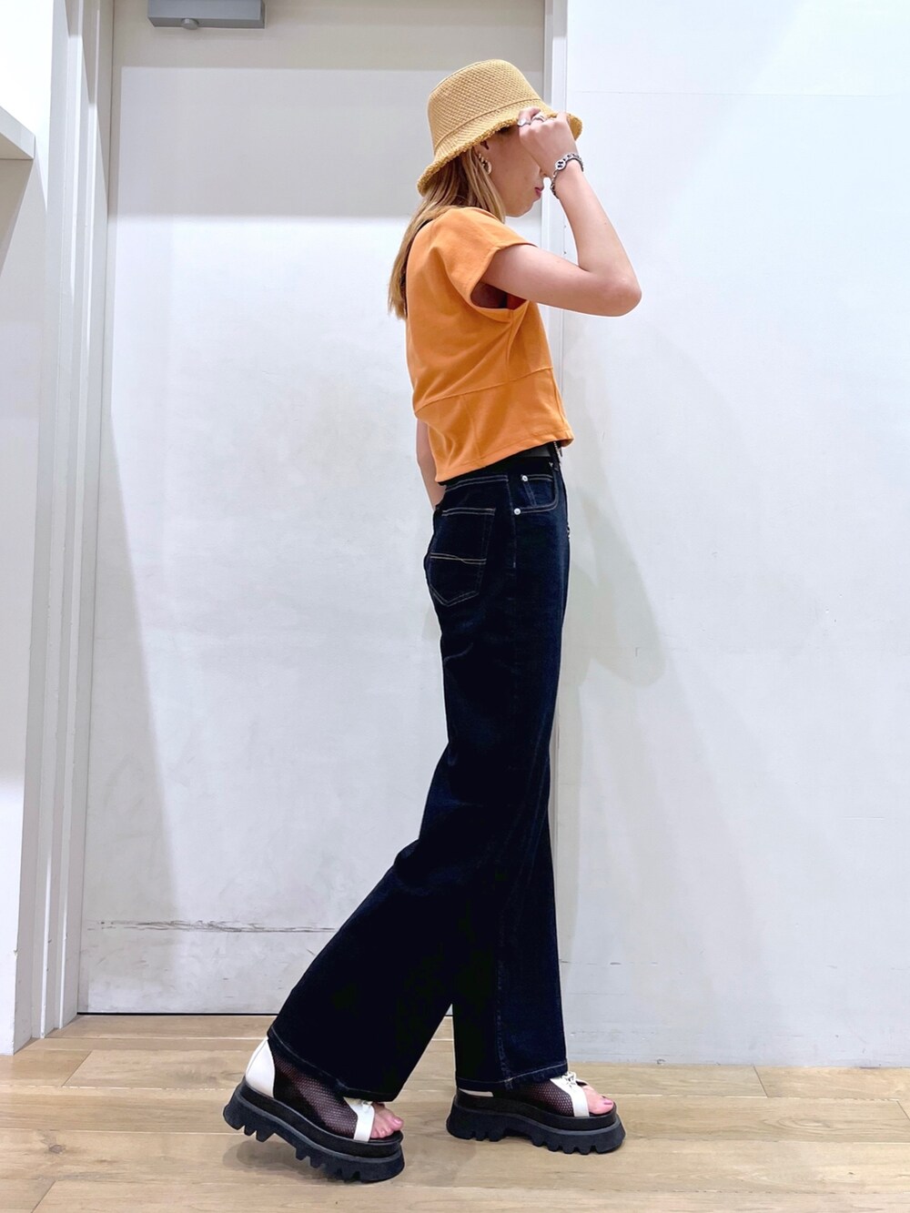 オレンジ系のTシャツ/カットソー、ブラウン系のショルダーバッグ、ブルー系のデニムパンツを着用したレディースの春コーディネートの4枚目の写真