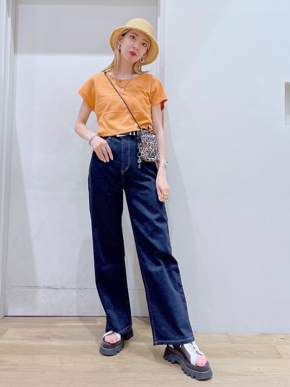 オレンジ系のTシャツ/カットソー、ブラウン系のショルダーバッグ、ブルー系のデニムパンツを着用したレディースの春コーディネートの2枚目の写真