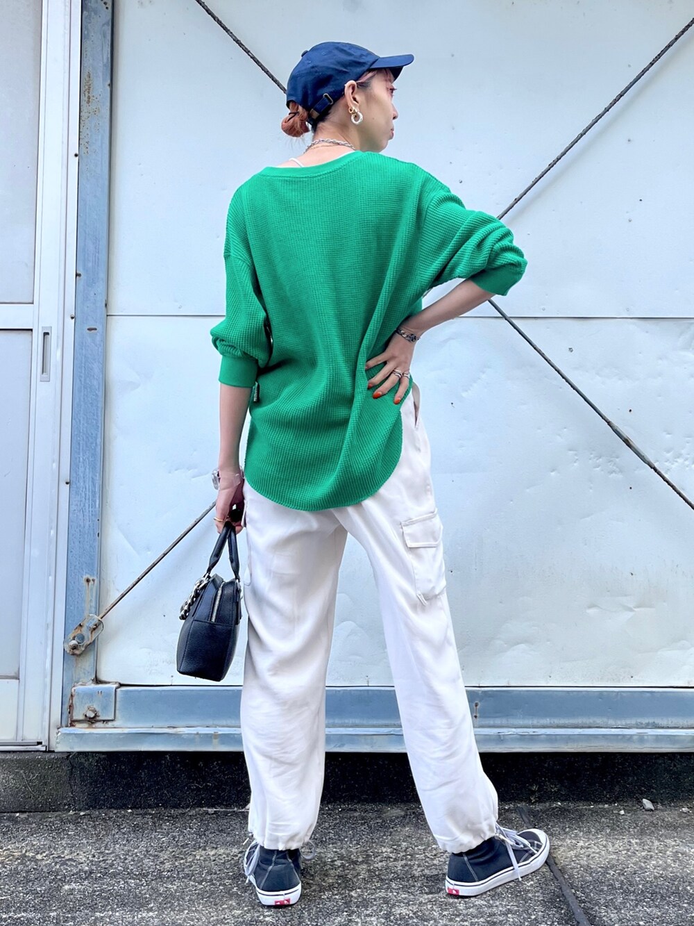 グリーン系のTシャツ/カットソー、ホワイト系のパンツ、ブラック系のショルダーバッグを着用したレディースの冬コーディネートの4枚目の写真