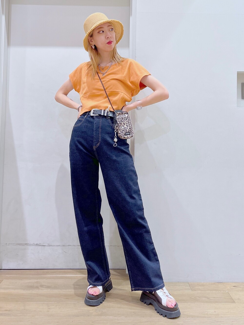 オレンジ系のTシャツ/カットソー、ブラウン系のショルダーバッグ、ブルー系のデニムパンツを着用したレディースの春コーディネートの3枚目の写真