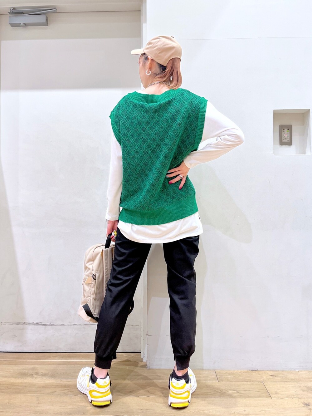 グリーン系のベスト、ホワイト系のTシャツ/カットソー、ベージュ系のバックパック/リュックを着用したレディースの冬コーディネートの4枚目の写真