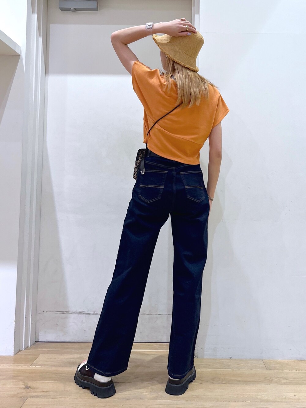 オレンジ系のTシャツ/カットソー、ブラウン系のショルダーバッグ、ブルー系のデニムパンツを着用したレディースの春コーディネートの5枚目の写真