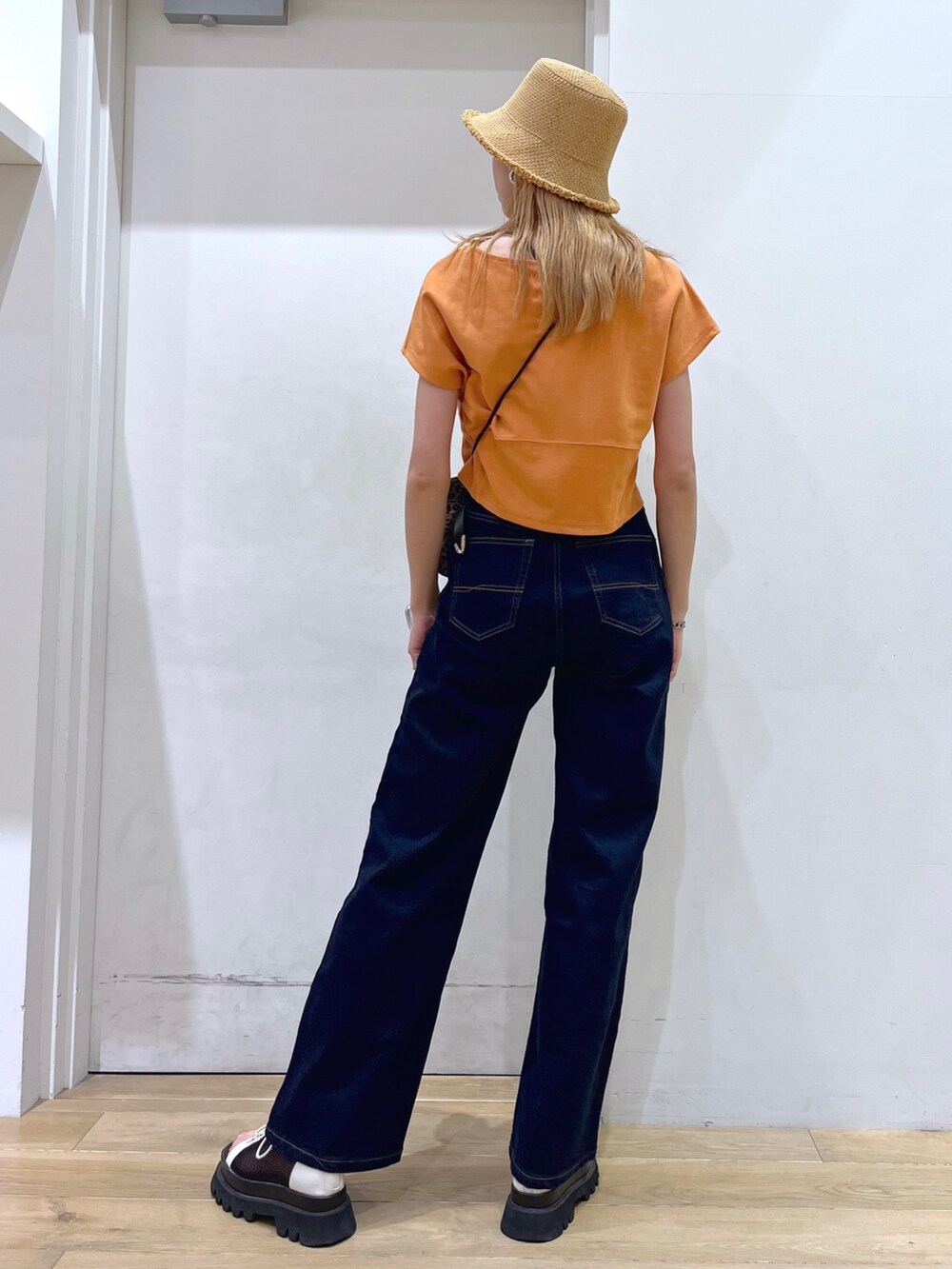 オレンジ系のTシャツ/カットソー、ブラウン系のショルダーバッグ、ブルー系のデニムパンツを着用したレディースの春コーディネートの6枚目の写真