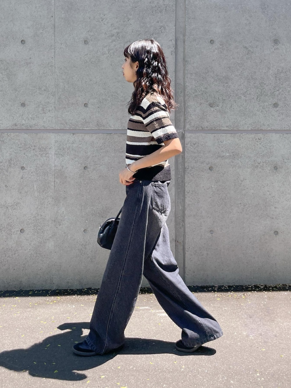 ブラック系のニット/セーター、ブラック系のデニムパンツを着用したレディースの夏コーディネートの2枚目の写真