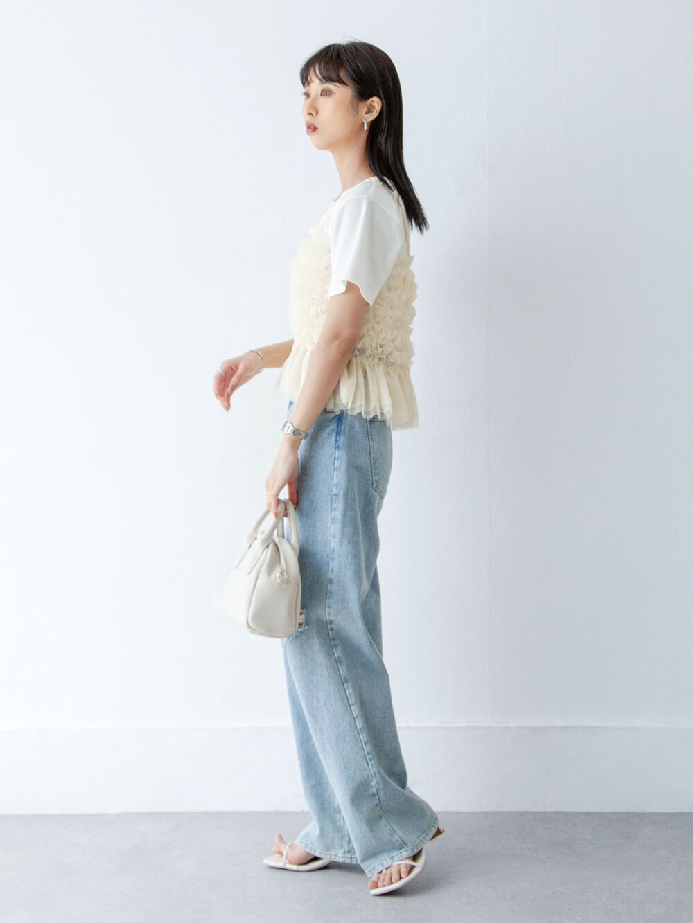 ホワイト系のキャミソール、ブルー系のデニムパンツを着用したレディースの夏コーディネートの2枚目の写真