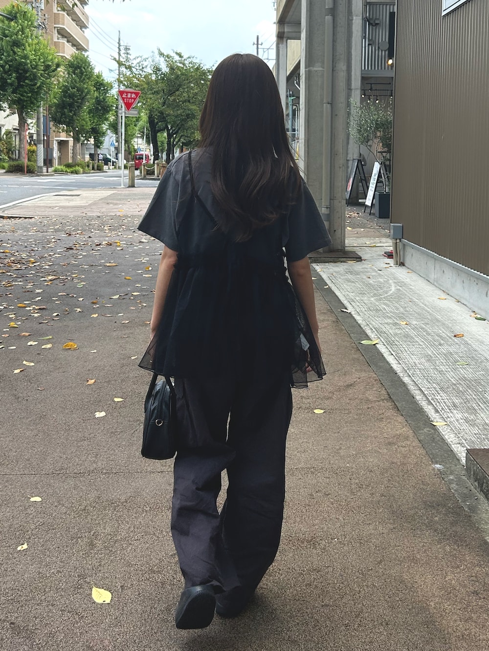 ブラック系のサンダル、グレー系のパンツ、ブラック系のショルダーバッグを着用したレディースの夏コーディネートの2枚目の写真