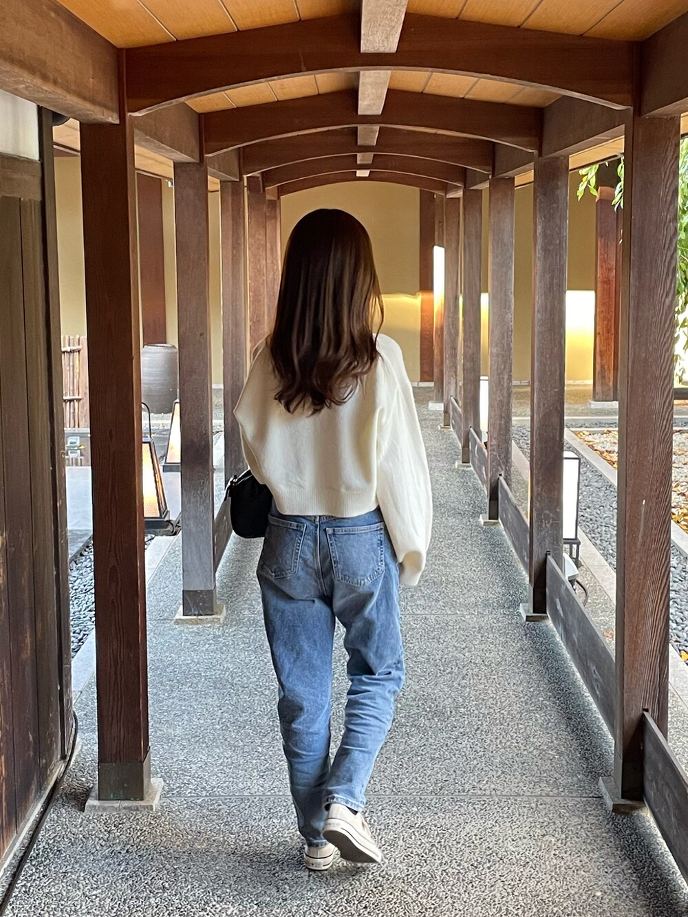 ホワイト系のニット/セーター、ブルー系のデニムパンツ、ブラック系のスニーカーを着用したレディースの秋コーディネートの2枚目の写真