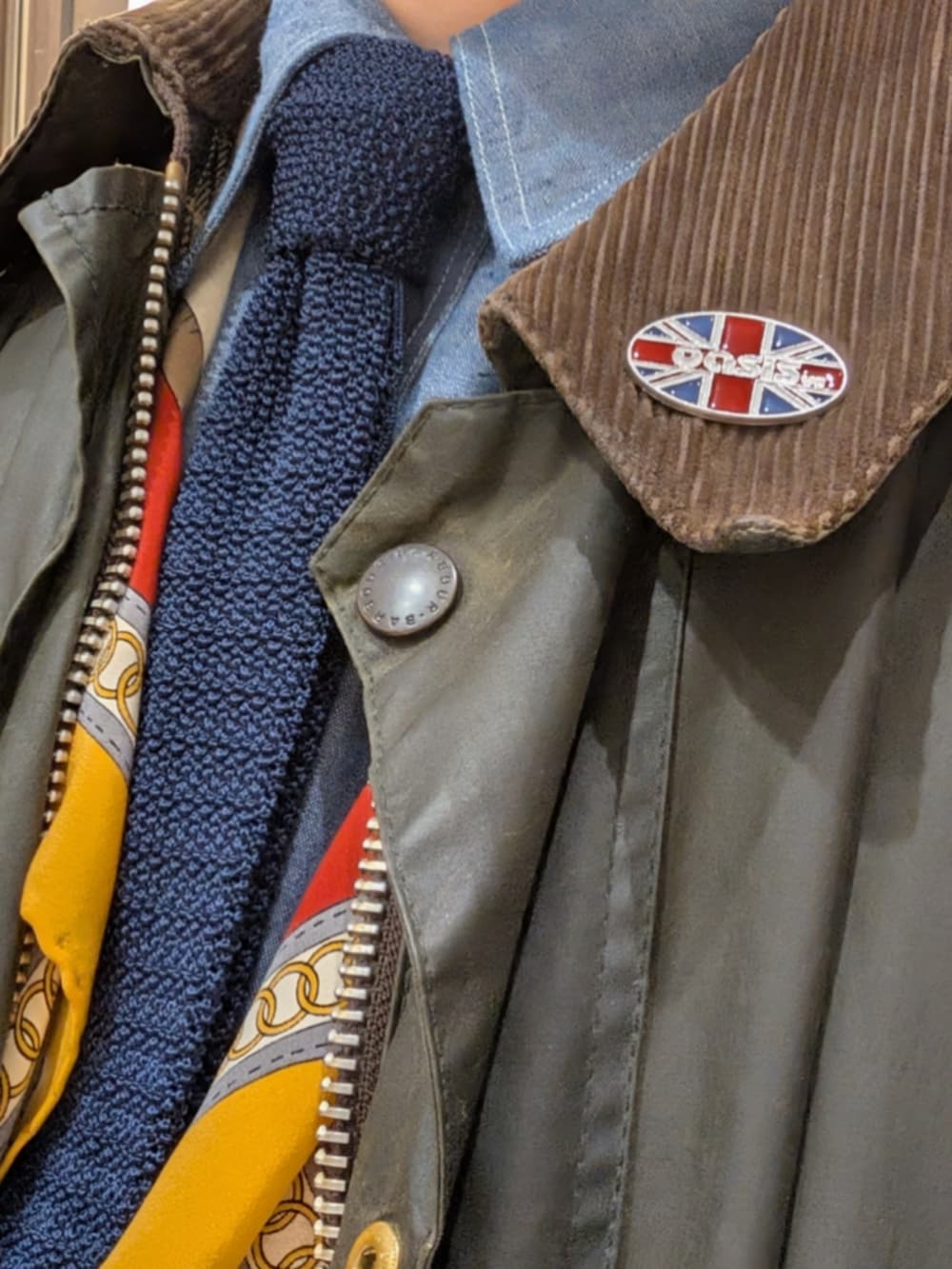 ブラック系のドレスシューズ、ブルー系のデニムパンツ、グリーン系のカバーオールを着用したメンズの冬コーディネートの2枚目の写真