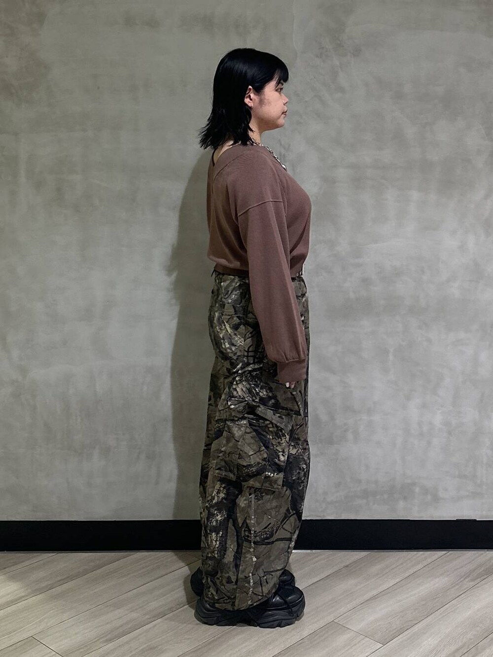 ブラック系のスニーカー、グリーン系のカーゴパンツ、ブラウン系のニット/セーターを着用したレディースの秋コーディネートの2枚目の写真