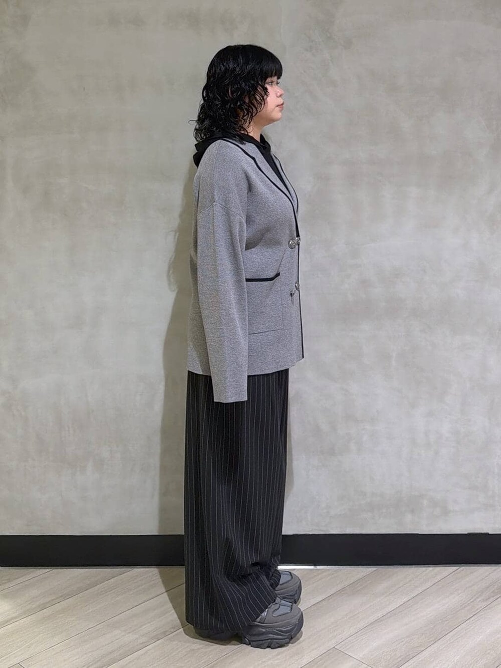 グレー系のスニーカー、ブラック系のスラックス、グレー系のテーラードジャケットを着用したレディースの冬コーディネートの2枚目の写真