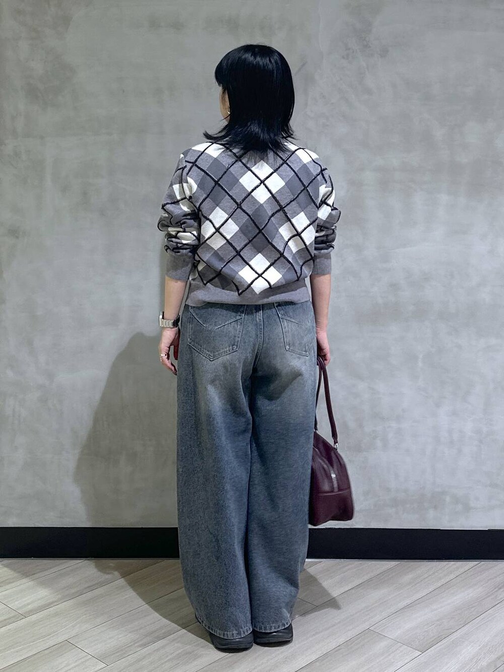 ブラック系のスニーカー、ブルー系のデニムパンツ、レッド系のボストンバッグを着用したレディースの秋コーディネートの3枚目の写真