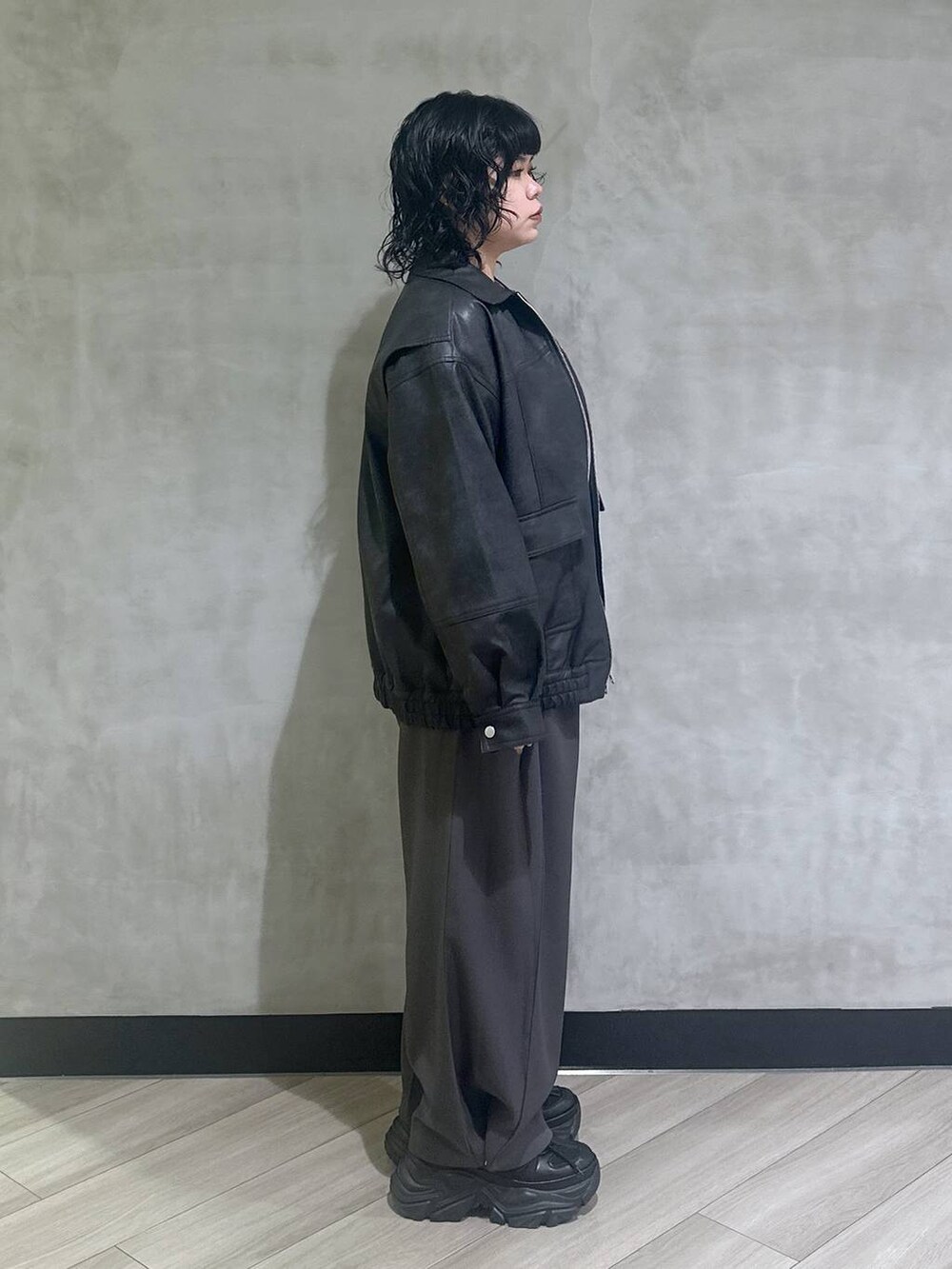 ブラック系のスニーカー、ブラック系のブルゾン、グレー系のスラックスを着用したレディースの秋コーディネートの2枚目の写真