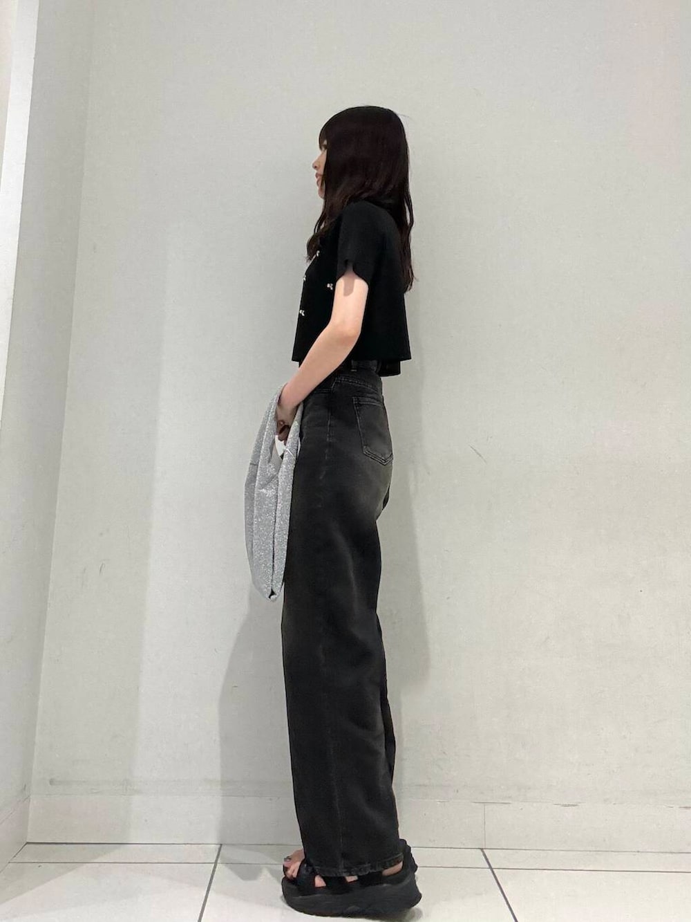 ブラック系のニット/セーター、シルバー系のトートバッグ、ブラック系のデニムパンツを着用したレディースの夏コーディネートの3枚目の写真