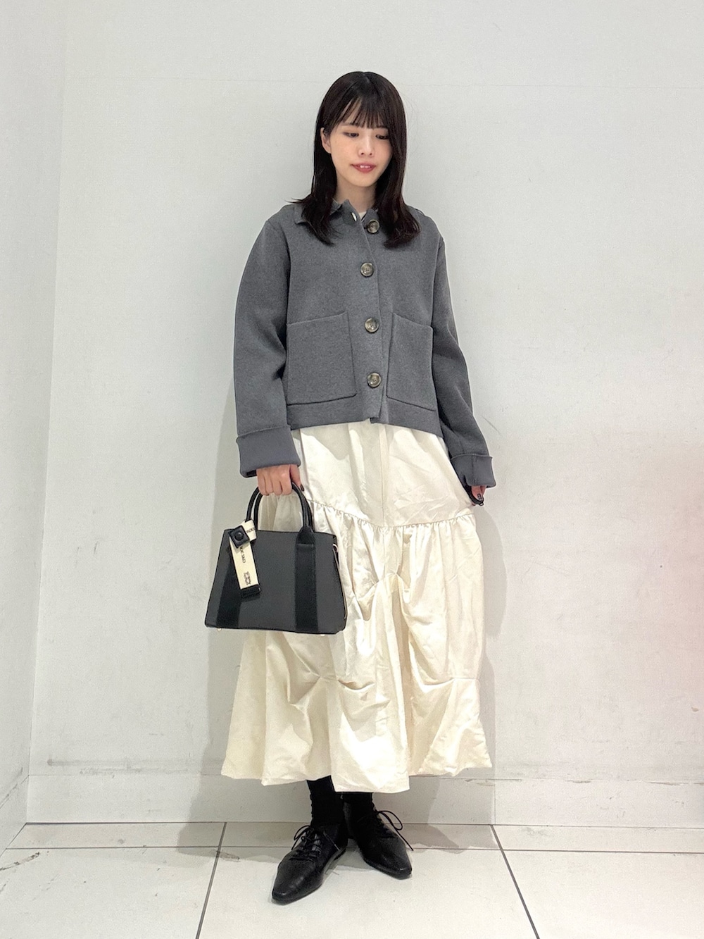 ホワイト系のスカート、ブラック系のその他シューズ、ブラック系のハンドバッグを着用したレディースの冬コーディネートの4枚目の写真