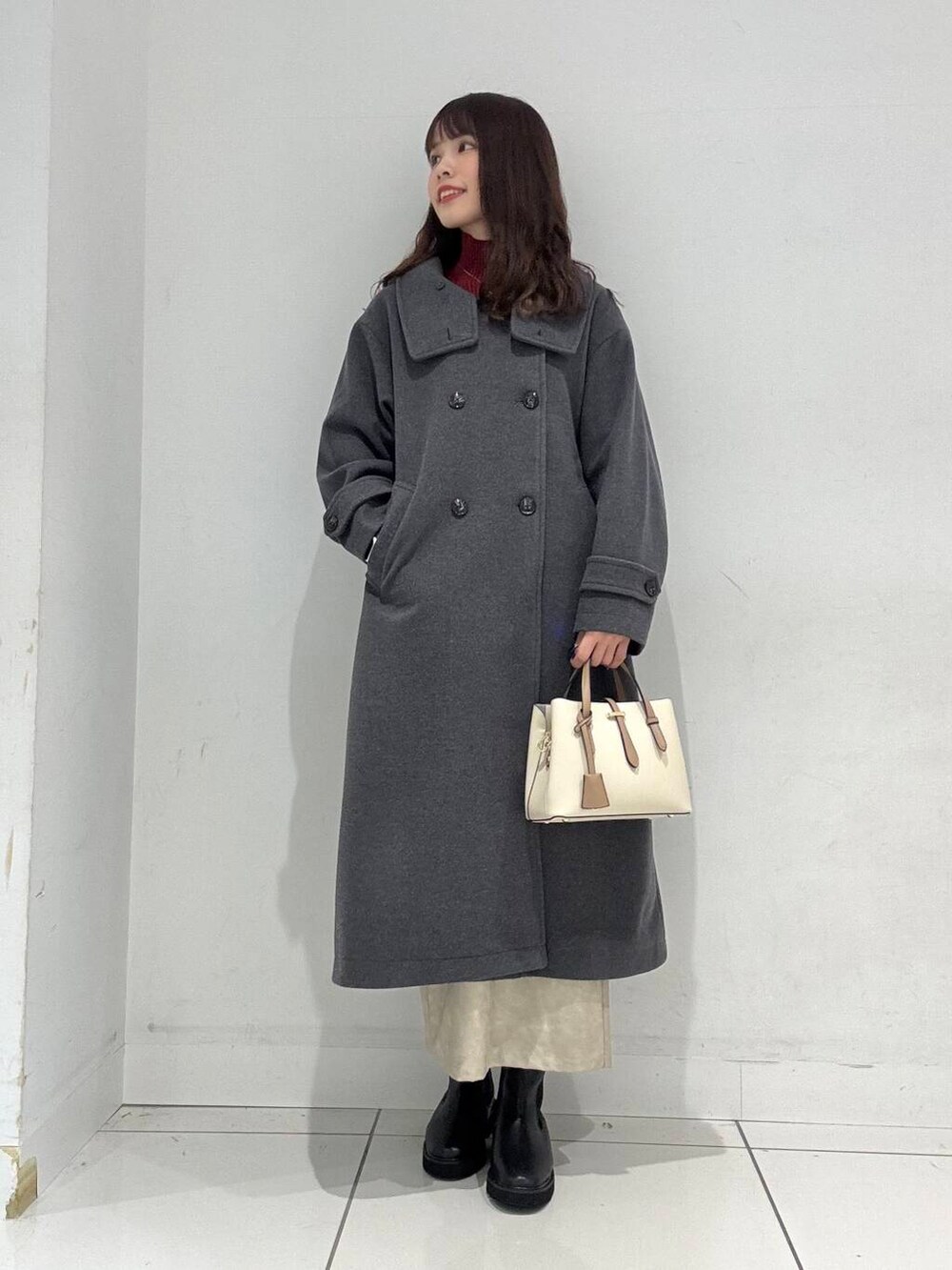 ホワイト系のハンドバッグ、レッド系のニット/セーター、ホワイト系のスカートを着用したレディースの冬コーディネートの2枚目の写真