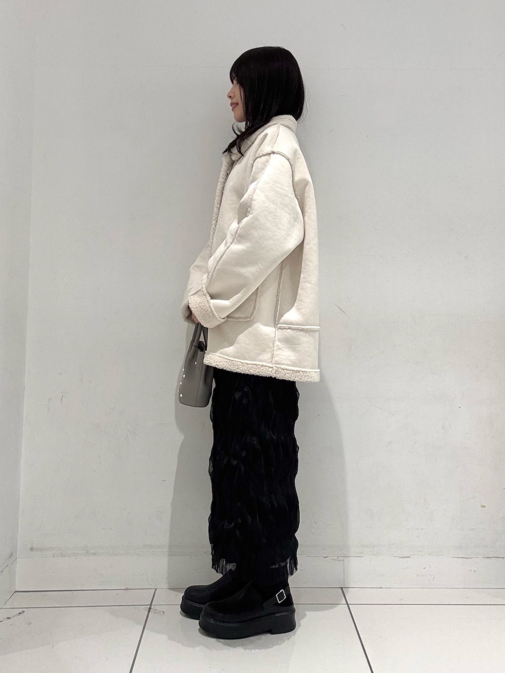 ブラック系のスカート、ブラック系のその他シューズ、グレー系のハンドバッグを着用したレディースの冬コーディネートの2枚目の写真