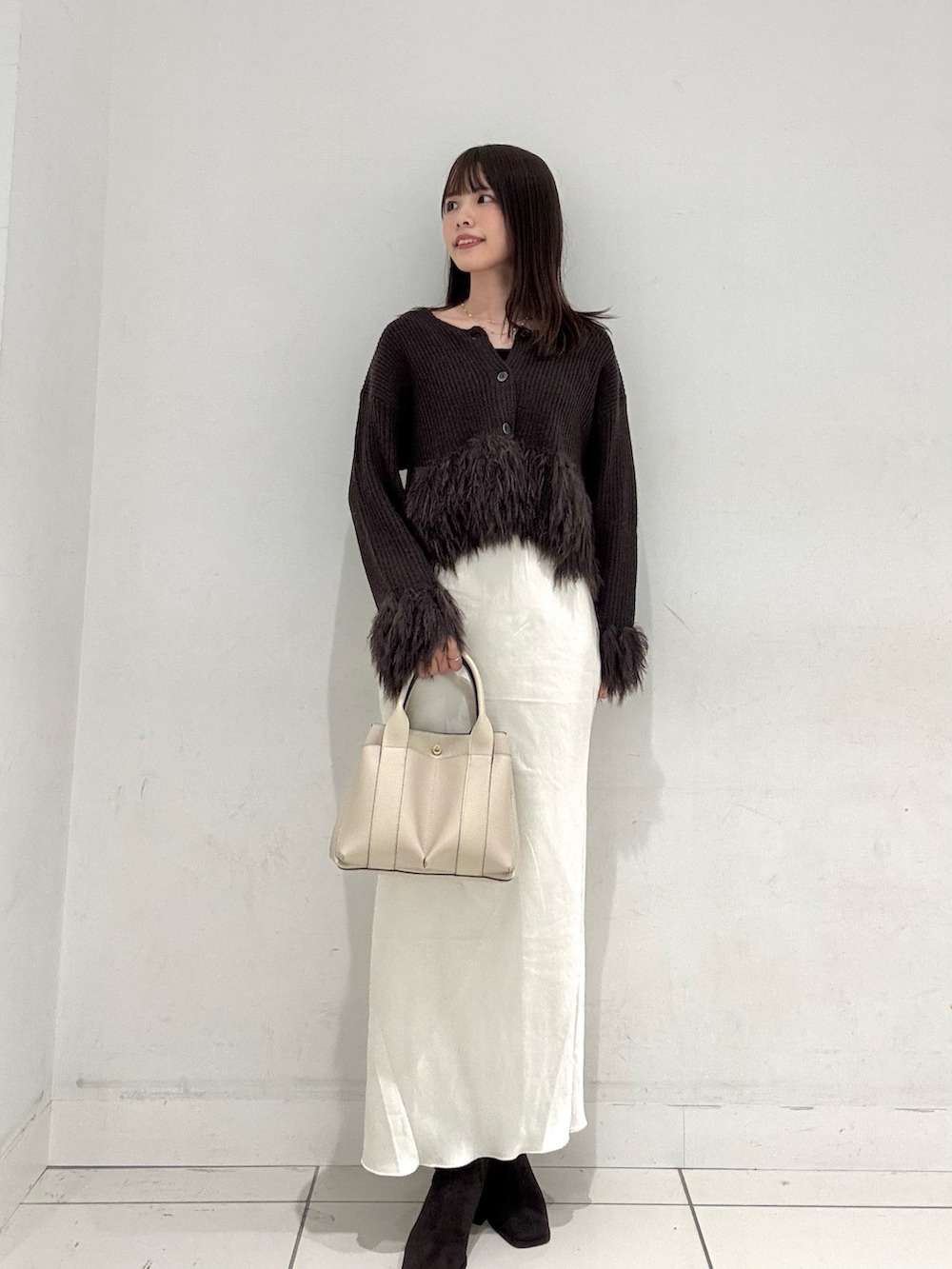 ブラウン系のニット/セーター、ホワイト系のスカート、ブラウン系のブーツを着用したレディースの秋コーディネートの4枚目の写真