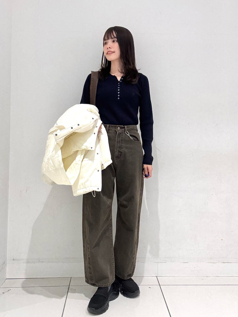 ホワイト系のダウンジャケット/コート、ブルー系のニット/セーター、ブラウン系のデニムパンツを着用したレディースの秋コーディネートの5枚目の写真