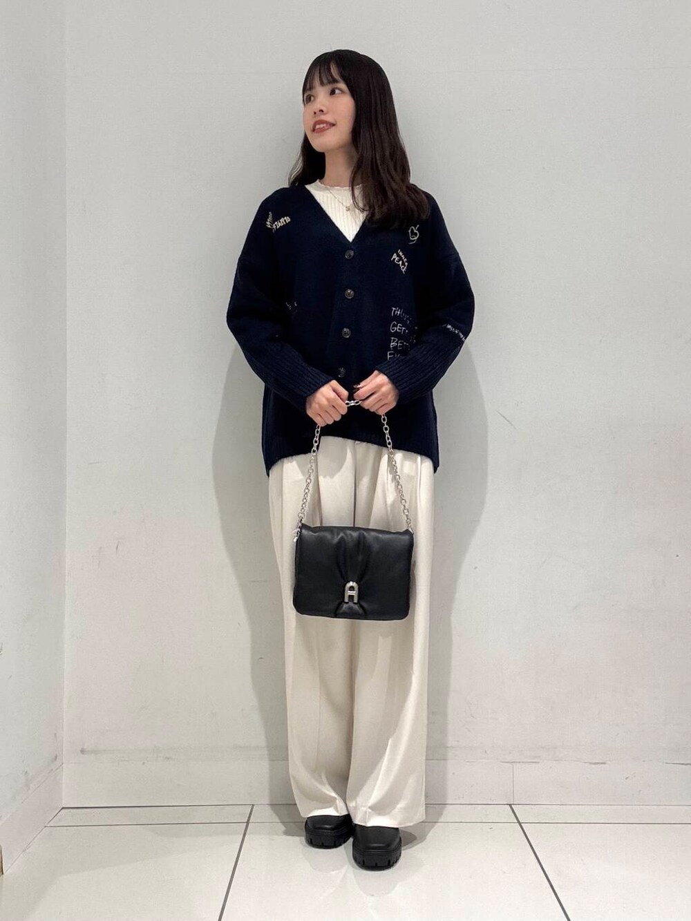 ブラック系のブーツ、ブラック系のショルダーバッグ、ブルー系のカーディガン/ボレロを着用したレディースの冬コーディネートの4枚目の写真