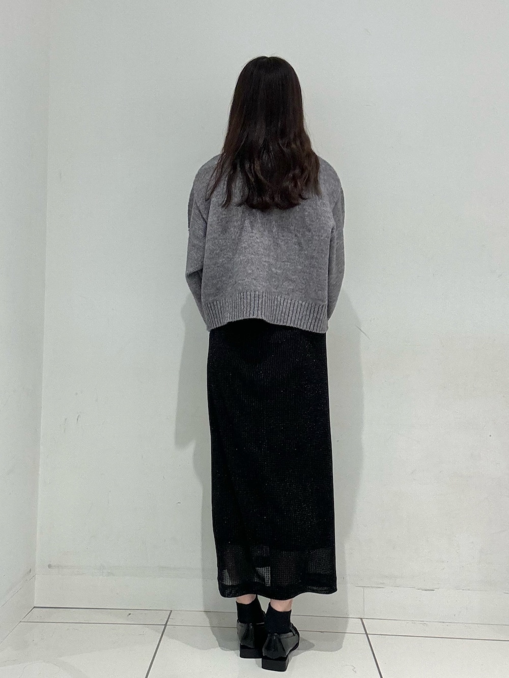 グレー系のニット/セーター、ブラック系のローファー、ホワイト系のハンドバッグを着用したレディースの秋コーディネートの3枚目の写真