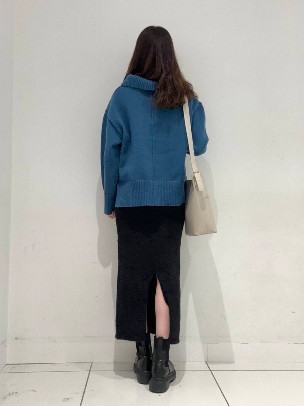 ベージュ系のショルダーバッグ、ブラック系のスカート、ブルー系のニット/セーターを着用したレディースの秋コーディネートの3枚目の写真
