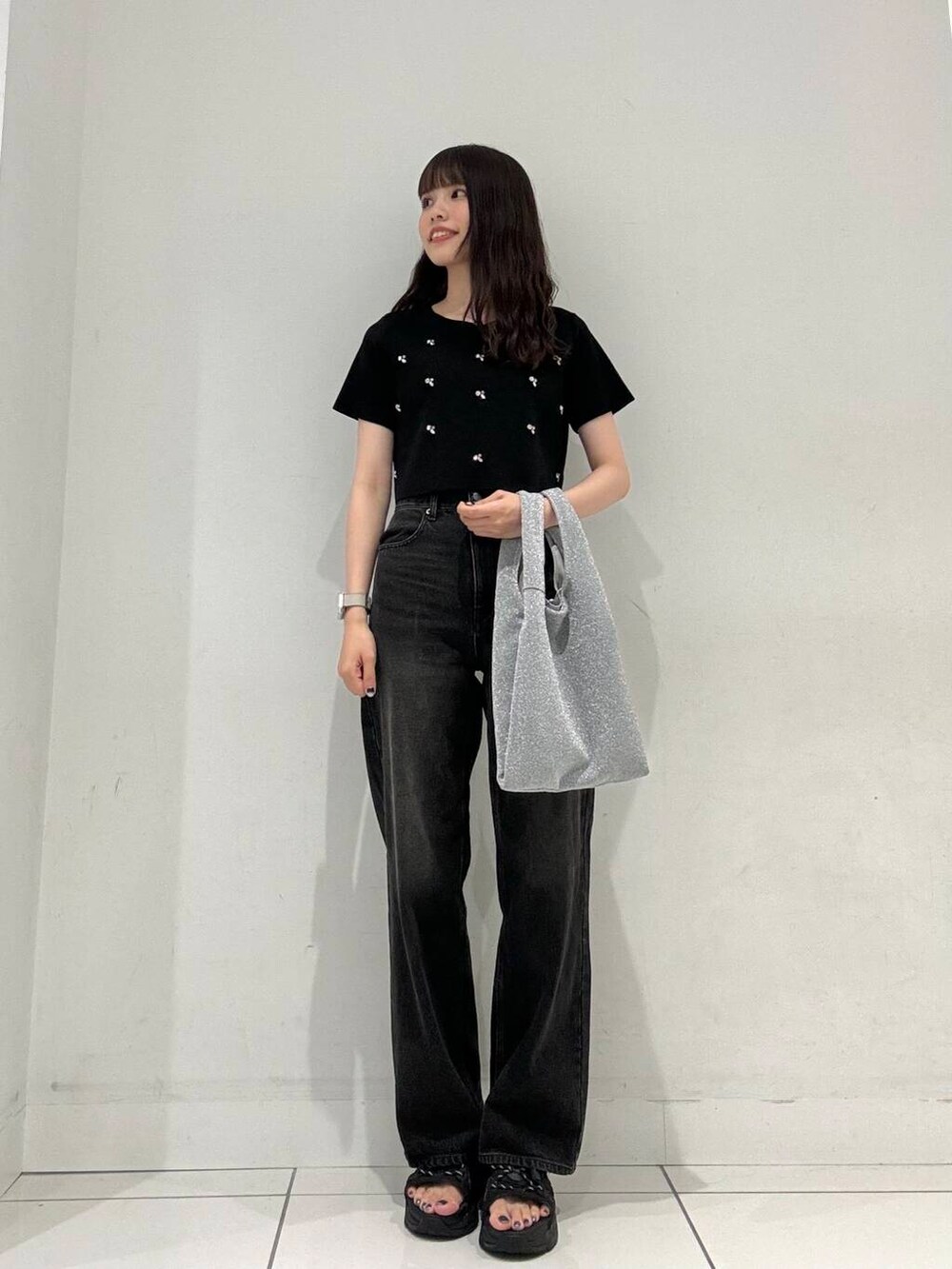 ブラック系のニット/セーター、シルバー系のトートバッグ、ブラック系のデニムパンツを着用したレディースの夏コーディネートの2枚目の写真