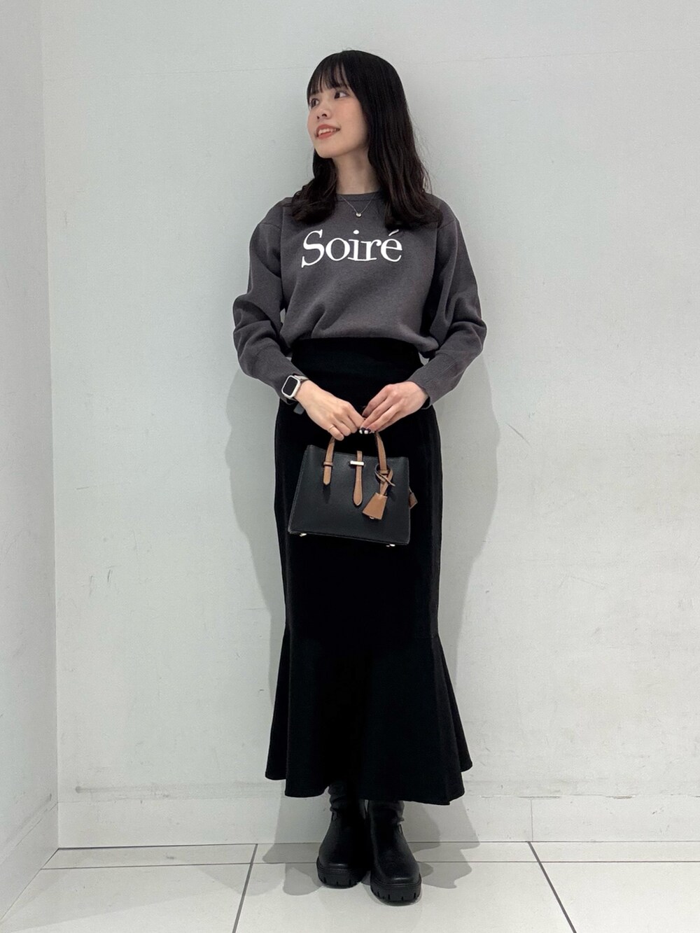 グレー系のニット/セーター、ホワイト系のダウンジャケット/コート、ブラック系のハンドバッグを着用したレディースの冬コーディネートの5枚目の写真