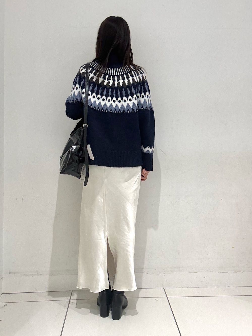 ブルー系のニット/セーター、ホワイト系のスカート、ブラック系のショルダーバッグを着用したレディースの秋コーディネートの3枚目の写真