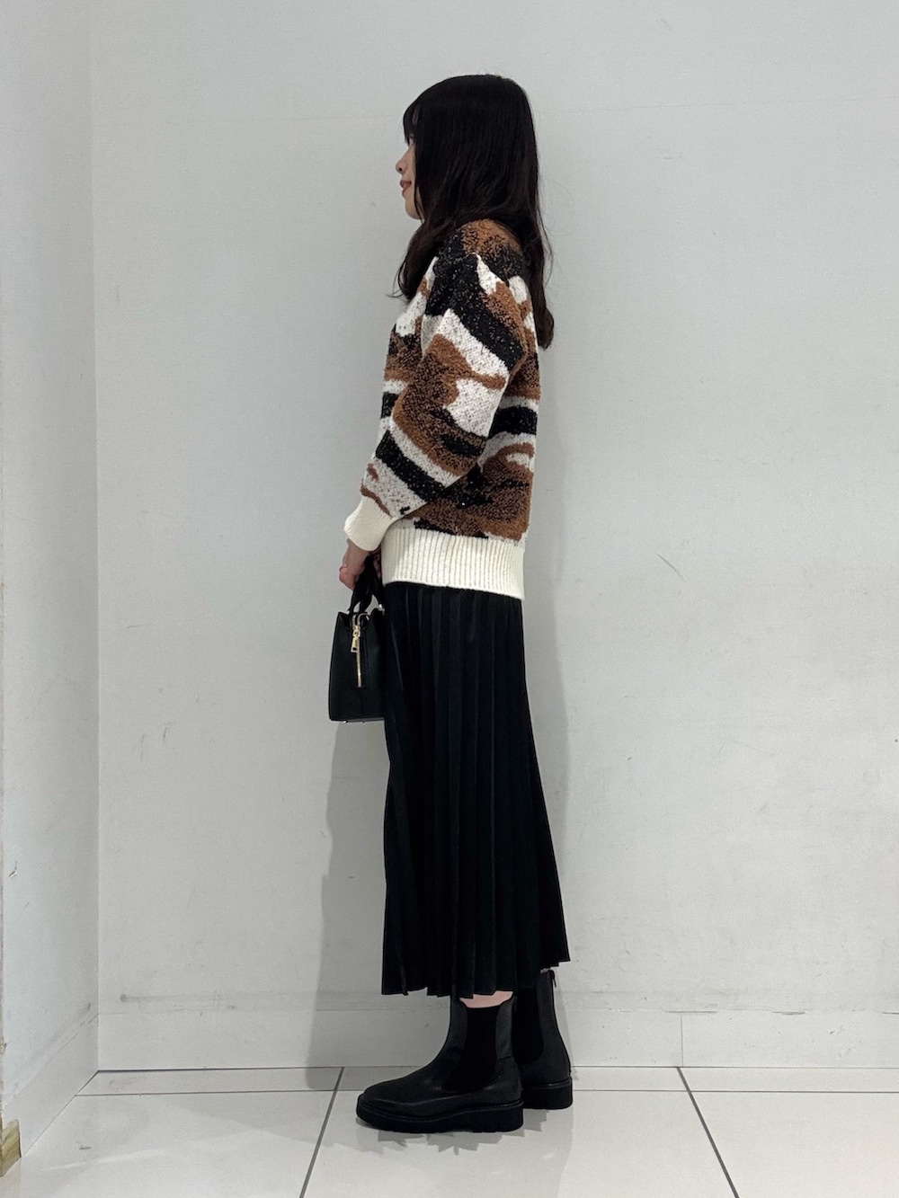 ホワイト系のニット/セーター、ブラック系のスカート、ブラック系のハンドバッグを着用したレディースの冬コーディネートの2枚目の写真