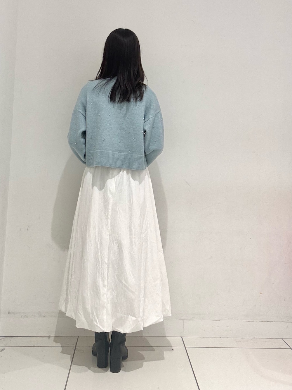 ホワイト系のスカート、グレー系のトートバッグ、ブラック系のブーツを着用したレディースの秋コーディネートの3枚目の写真