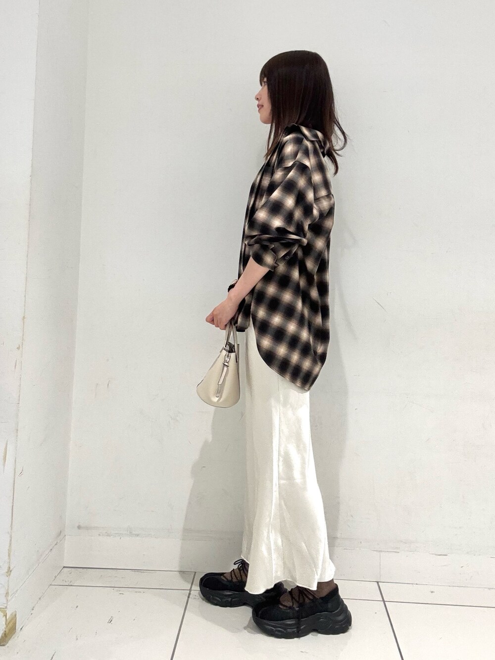 ブラウン系のシャツ/ブラウス、ホワイト系のスカート、ブラック系のスニーカーを着用したレディースの秋コーディネートの2枚目の写真