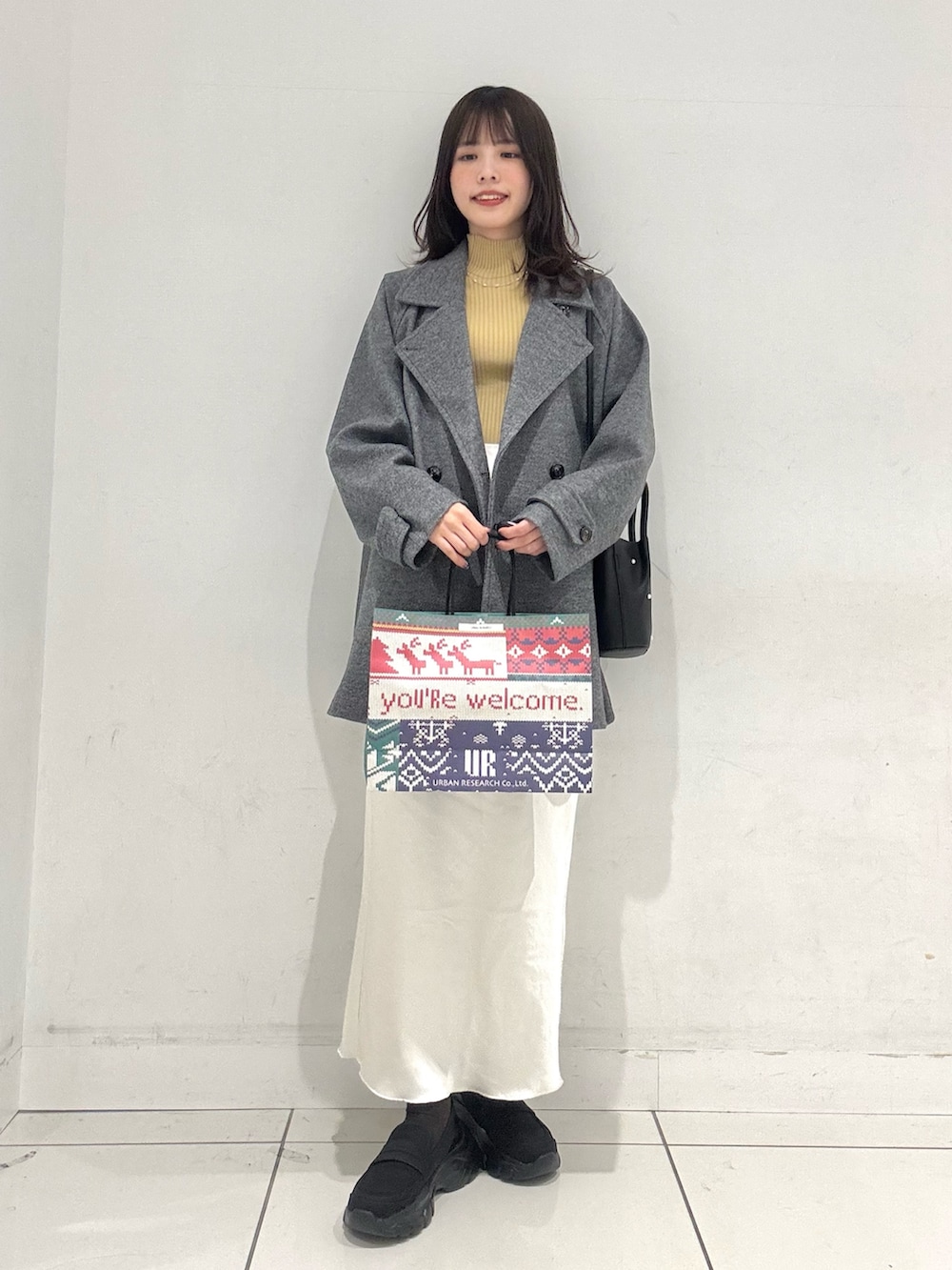 グレー系のその他アウター、イエロー系のニット/セーター、ホワイト系のスカートを着用したレディースの冬コーディネートの4枚目の写真