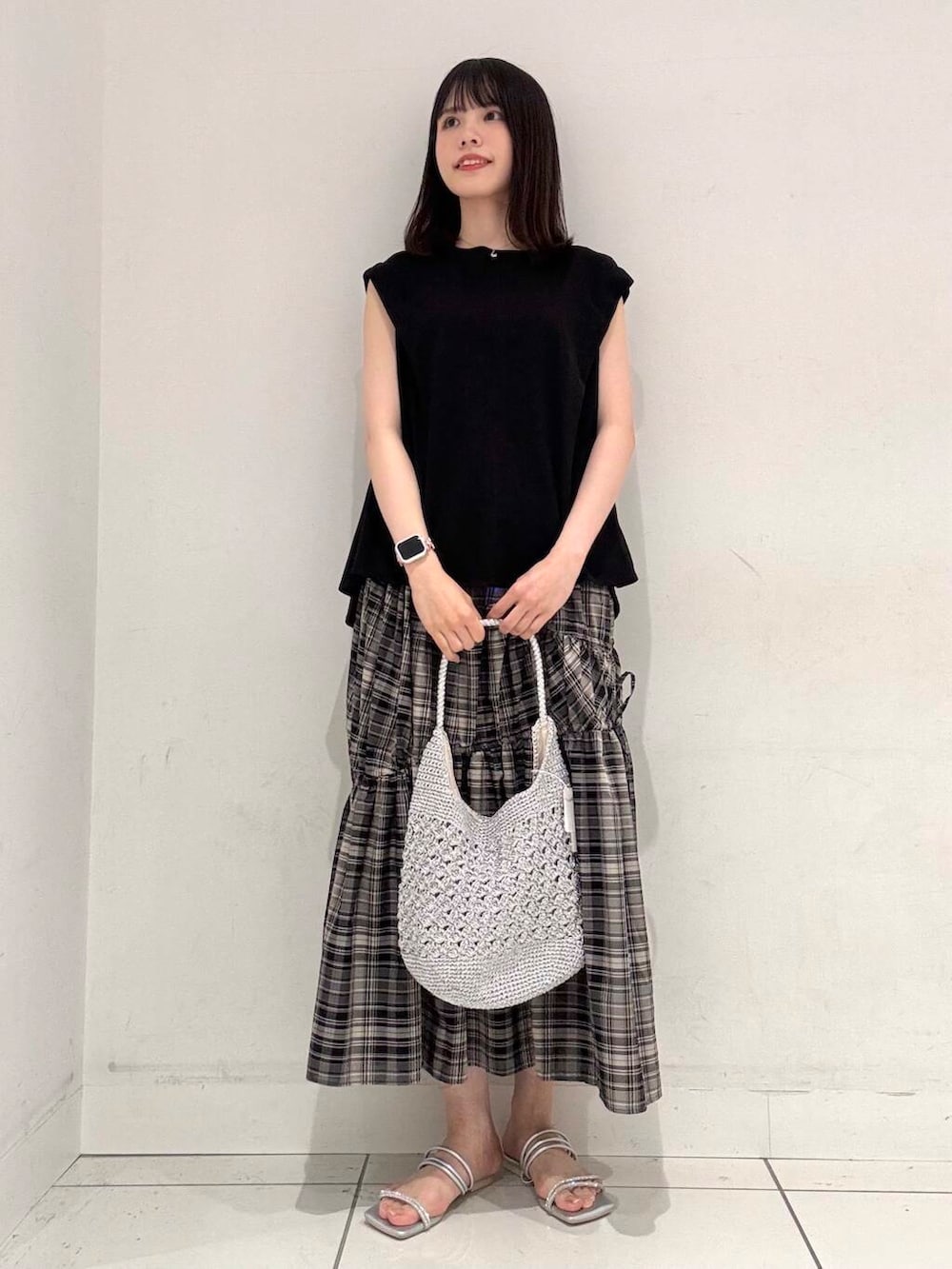 シルバー系のハンドバッグ、シルバー系のサンダル、ブラック系のTシャツ/カットソーを着用したレディースの夏コーディネートの4枚目の写真