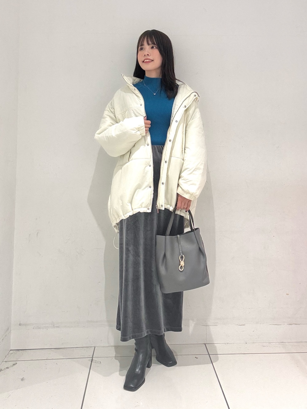 ブルー系のニット/セーター、ホワイト系のダウンジャケット/コート、グレー系のスカートを着用したレディースの秋コーディネートの4枚目の写真