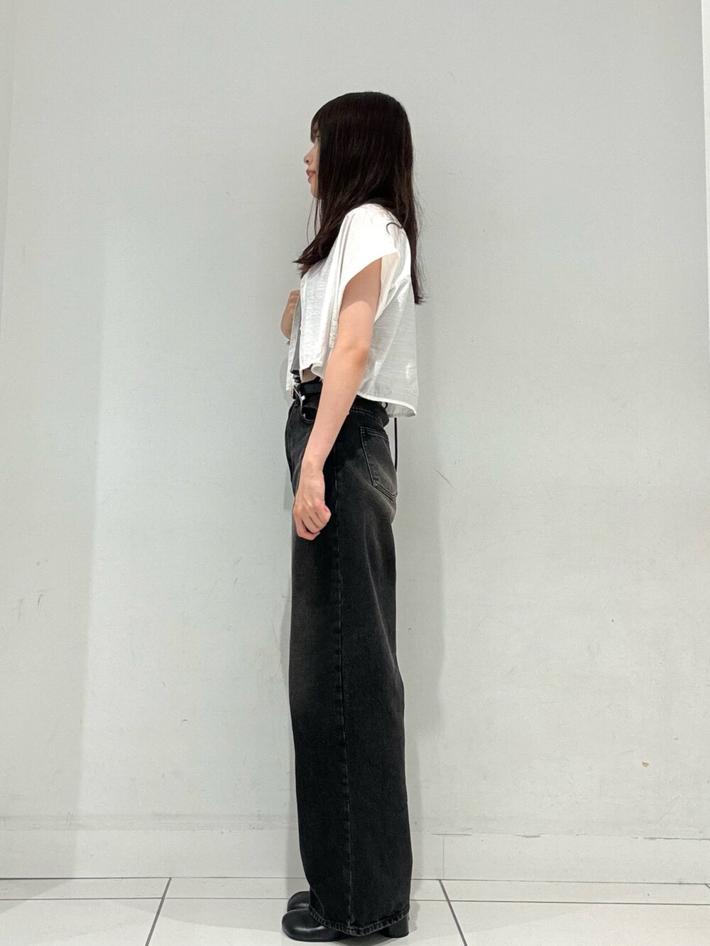 グレー系のタンクトップ、ブラック系のデニムパンツ、ブラック系のサンダルを着用したレディースの秋コーディネートの3枚目の写真