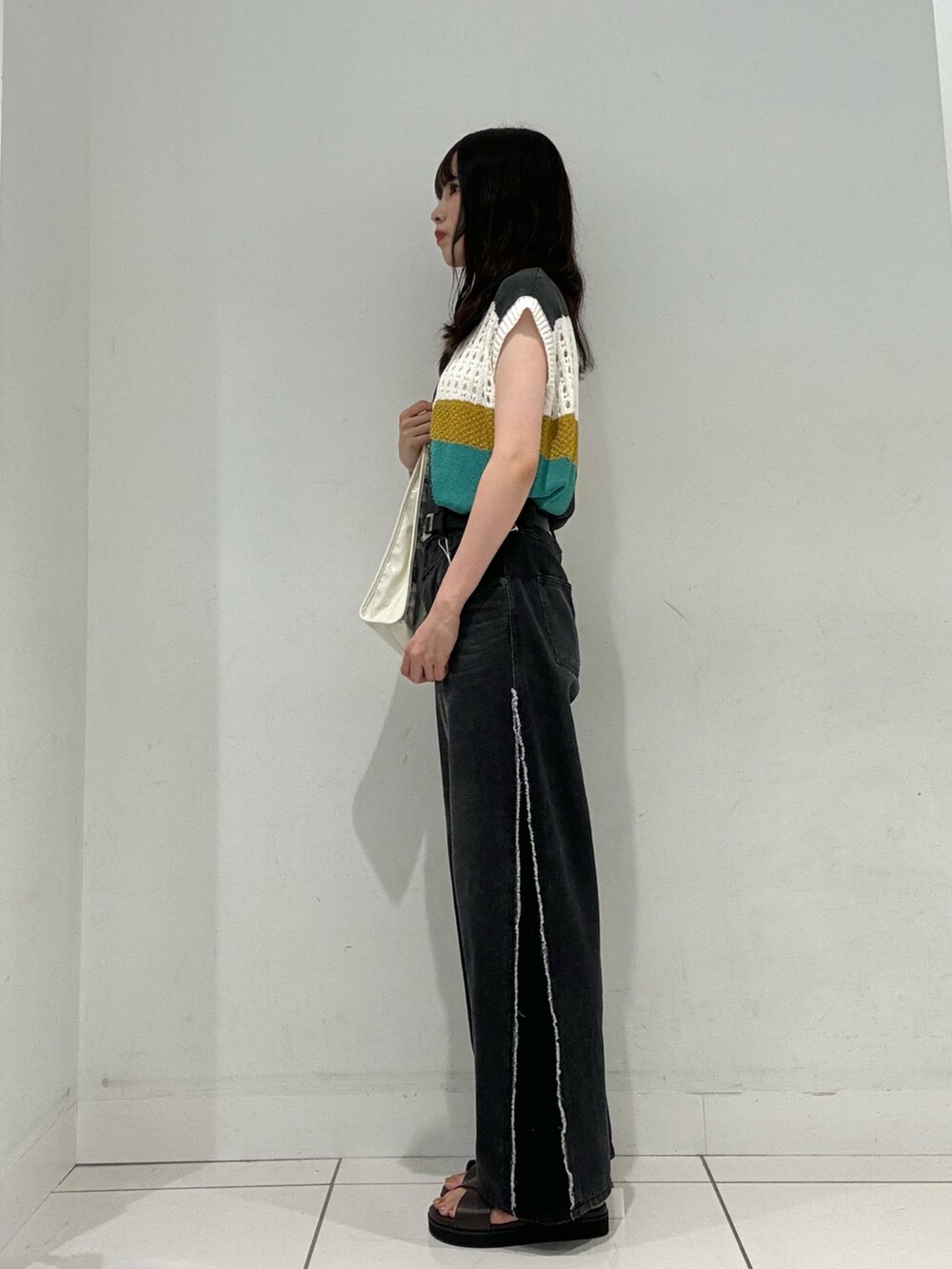 ブラウン系のサンダル、ブラック系のデニムパンツ、グレー系のベストを着用したレディースの夏コーディネートの3枚目の写真