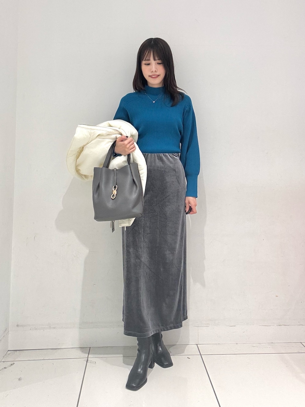 ブルー系のニット/セーター、ホワイト系のダウンジャケット/コート、グレー系のスカートを着用したレディースの秋コーディネートの5枚目の写真