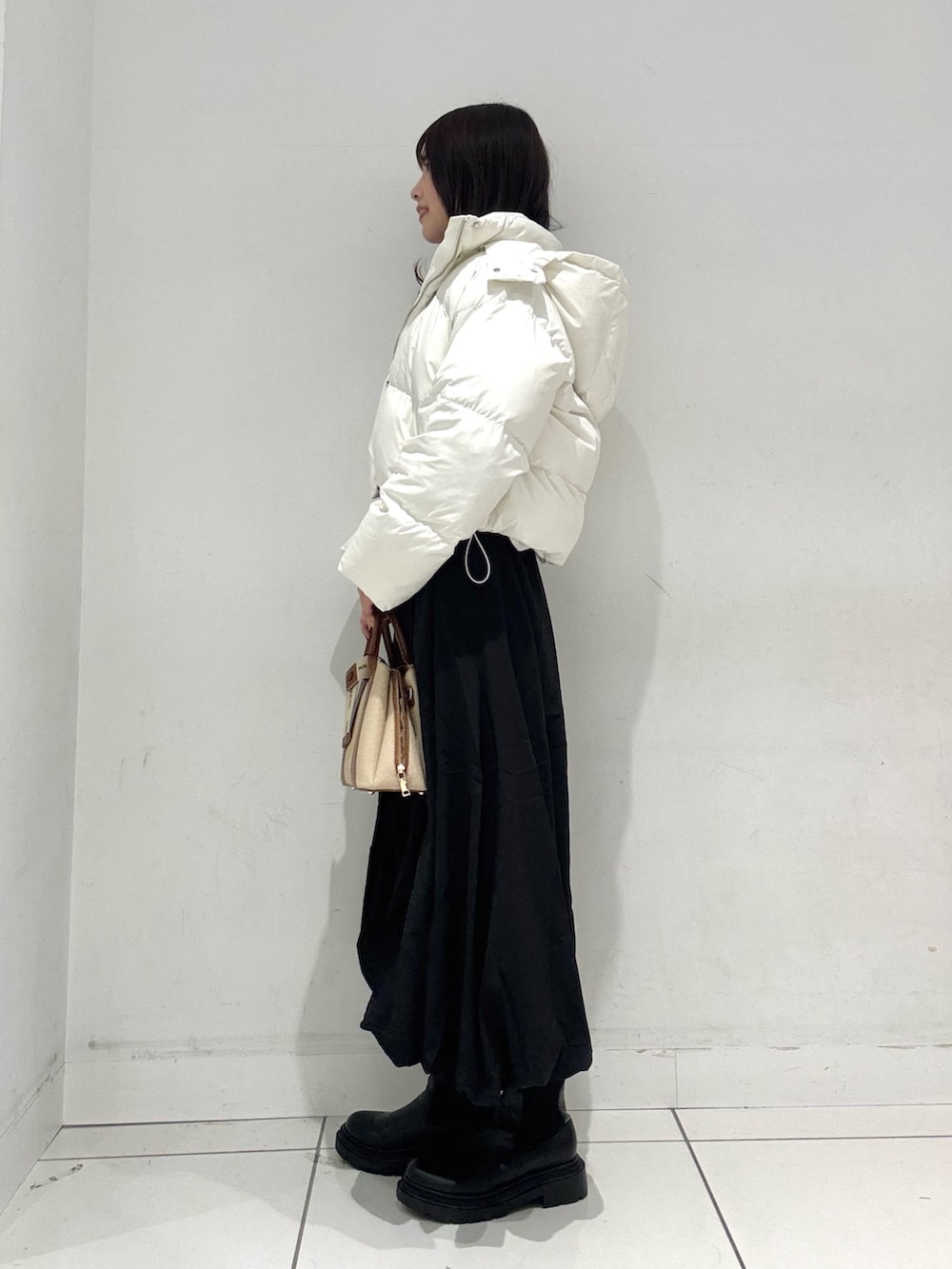 ブラック系のスカート、ブラウン系のニット/セーター、ホワイト系のダウンジャケット/コートを着用したレディースの冬コーディネートの3枚目の写真