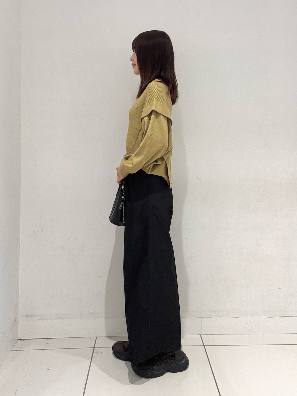 イエロー系のニット/セーター、ブラック系のその他パンツ、ブラック系のショルダーバッグを着用したレディースの秋コーディネートの2枚目の写真